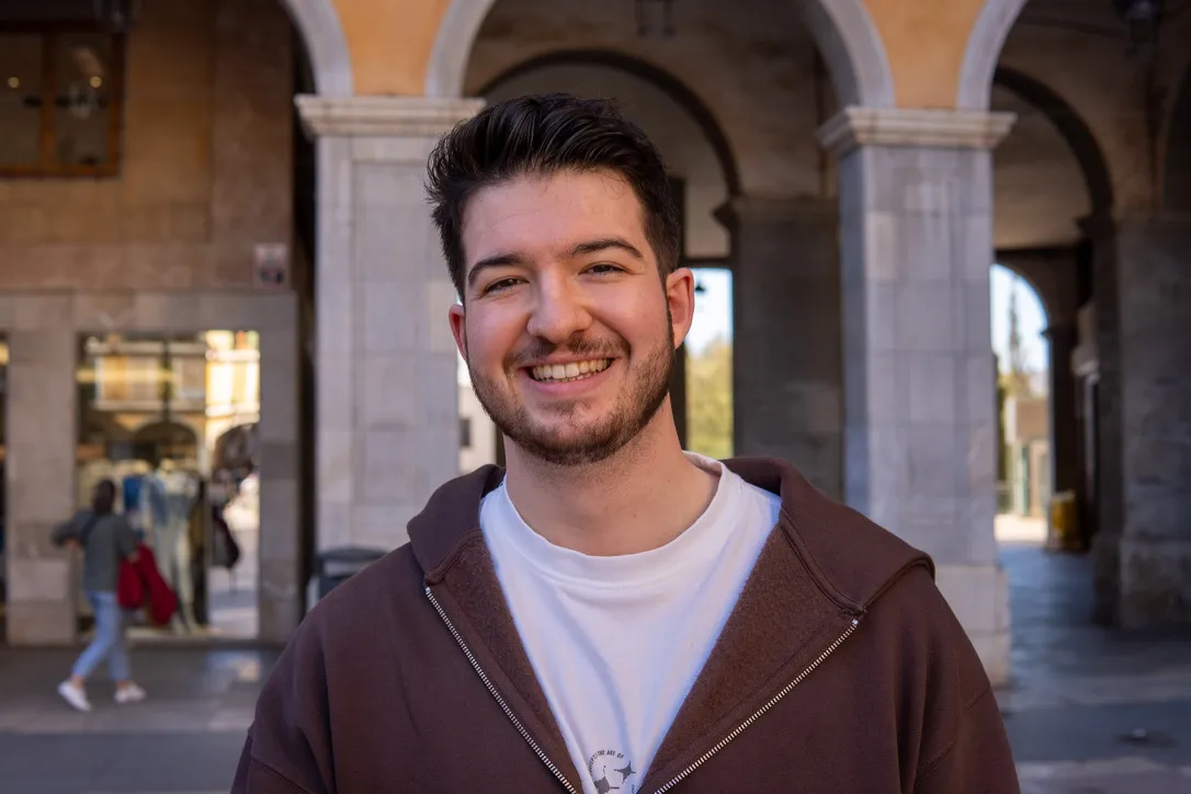 Fabian Bitzer smiling in a brown hoodie under the arches of an arcade.